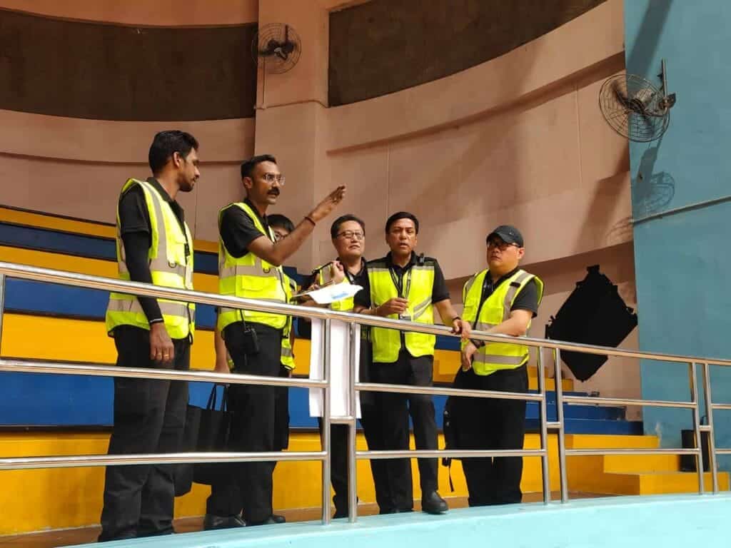 Security in hi-vis vests standing over a railing, one of them points at something as if assessing the area. Risk mitigation is a service provided by event security companies