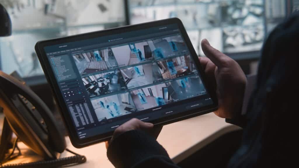 Security staff monitoring AI-powered CCTV cameras through a tablet as part of smart building security solutions