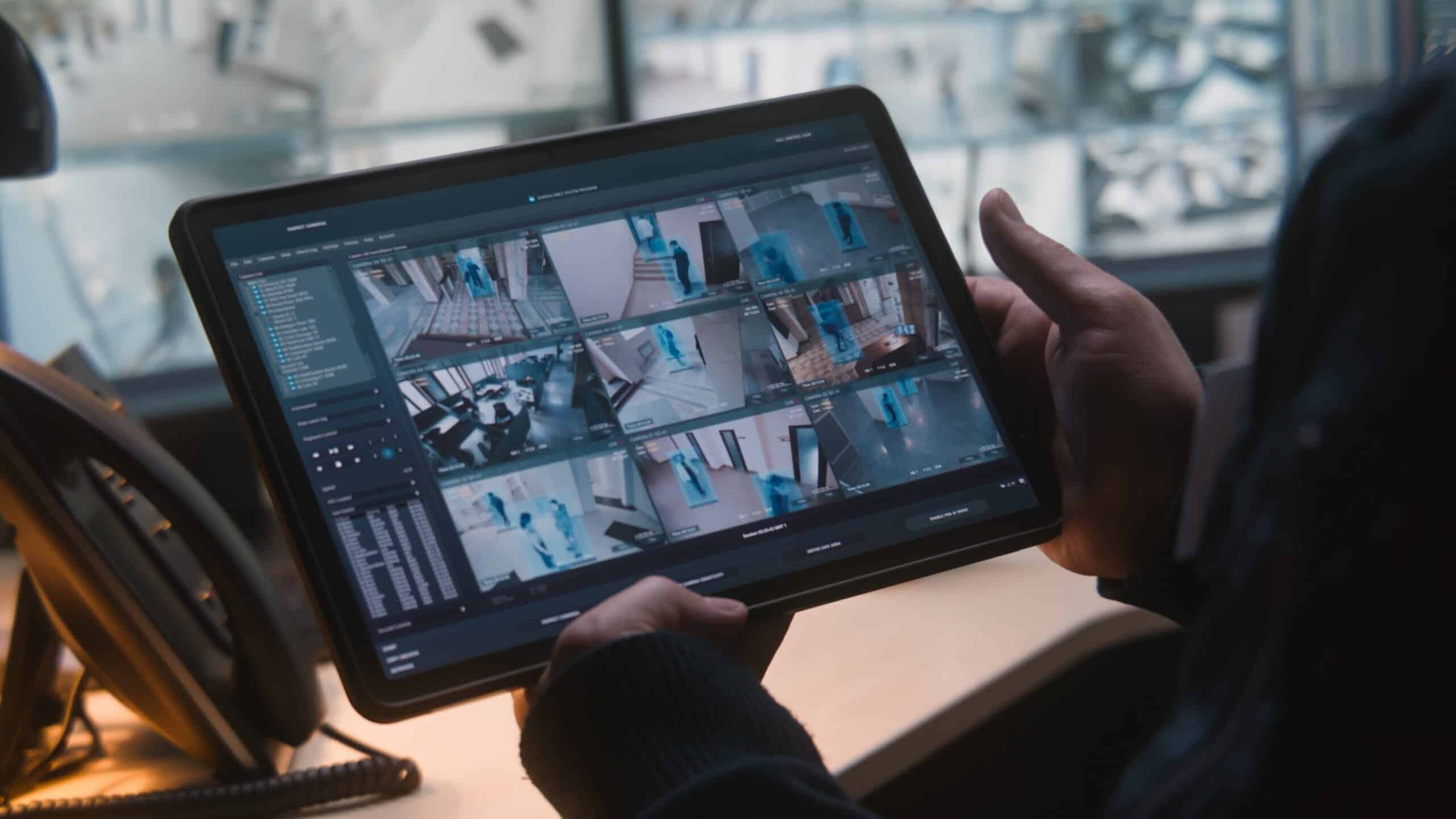 Security staff monitoring AI-powered CCTV cameras through a tablet as part of smart building security solutions
